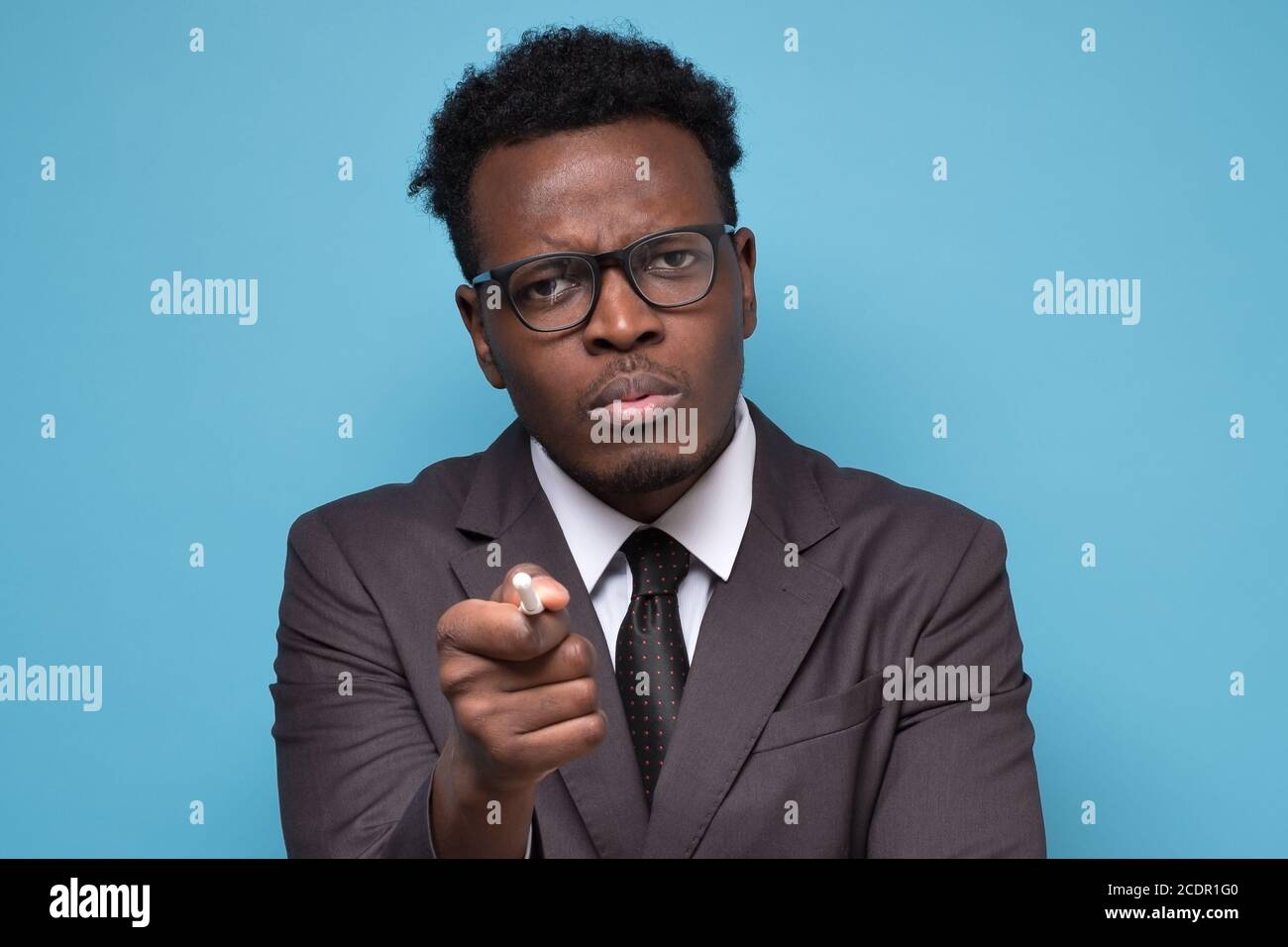 Afrikanischer Mann zeigt den Finger, zeigt Richtung zur Kamera und schaut genervt Stockfoto