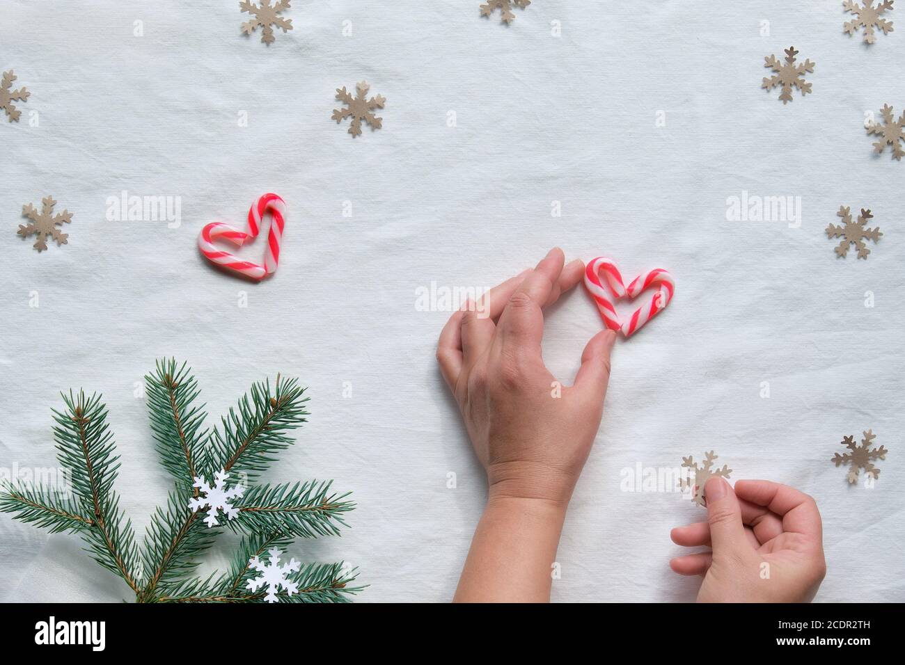 Weihnachten flach lag mit weiblichen Händen halten Herz aus Süßigkeiten Stöcke und Handwerk Papier Schneeflocke Silhouette. Zero Waste umweltfreundliche Einrichtung aus natürlichen f Stockfoto
