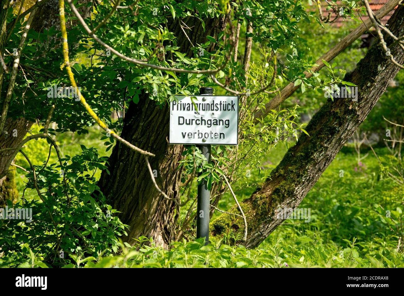 Anmeldung in deutscher Sprache vor einem bewachsenen Grundstück - Privateigentum - keine Passage (Privatgrundstück Durchgang verboten). Stockfoto