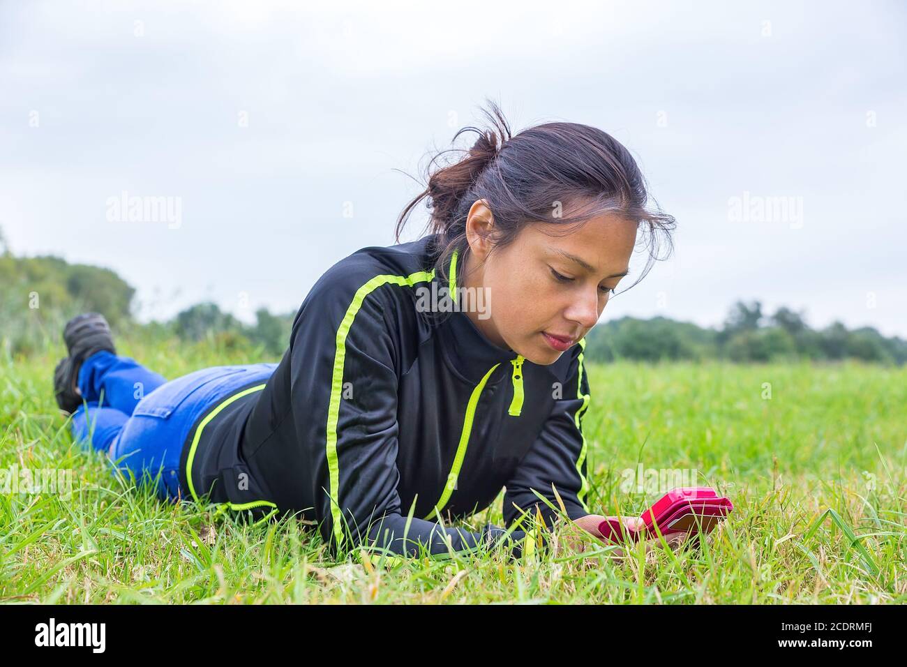 Frau im Gras liegend und Mobiltelefon bediente Stockfoto