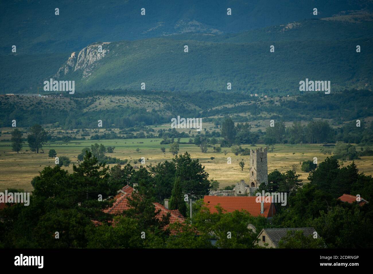 Ein kleines Dorf mit vielen verlassenen Häusern und einem alten Kirchturm liegt auf Ebenen in der Nähe von Ausläufern. Stockfoto