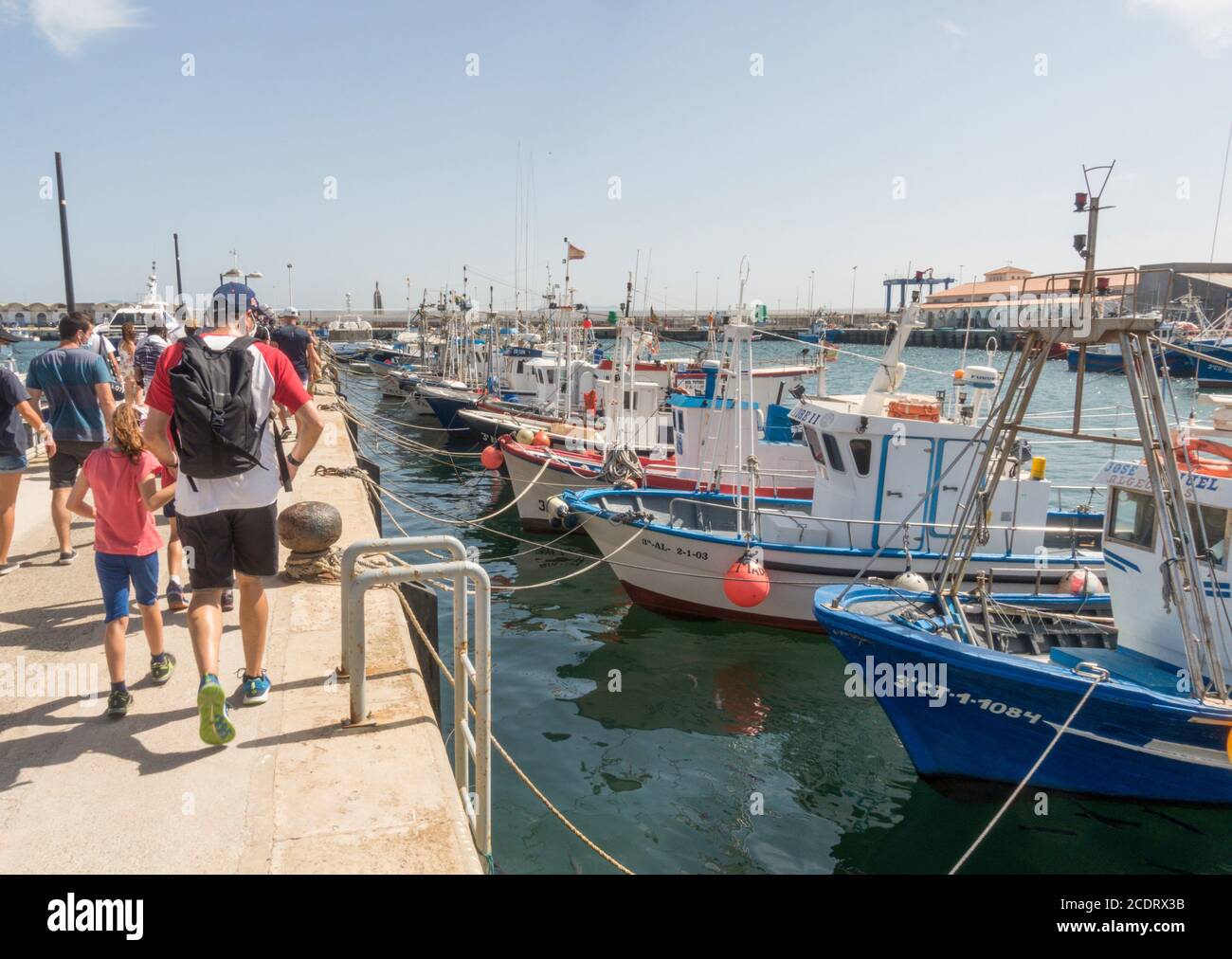 Tarifa Spanien. Touristen zu Fuß zum Boot neben Fischerbooten am Fischerhafen von Tarifa, Costa de la Luz, Andalusien, Spanien. Stockfoto