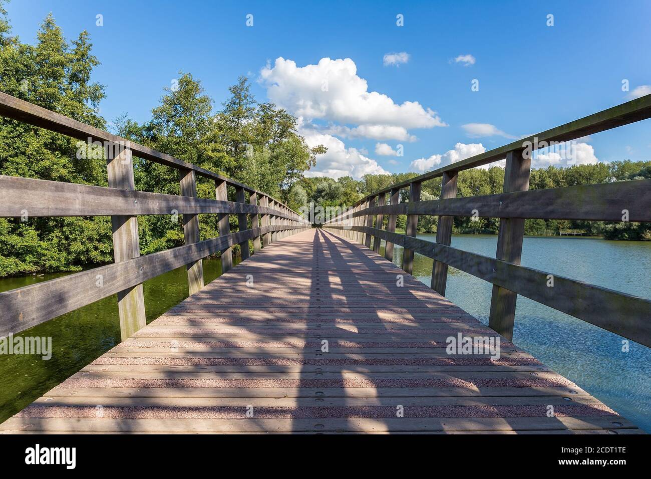 Lange Holzbrücke über Wasser des Teiches Stockfoto