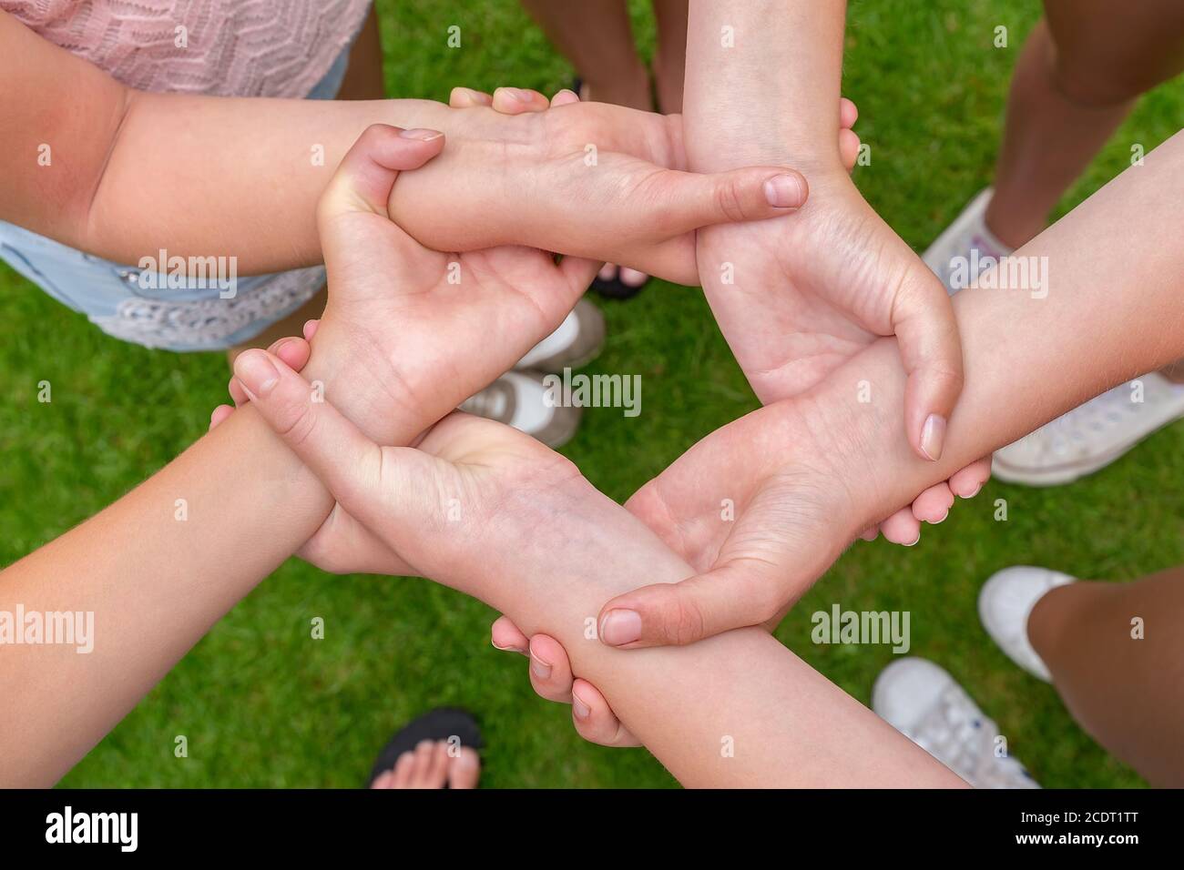 Arme mit Händen von Mädchen halten sich gegenseitig Stockfoto