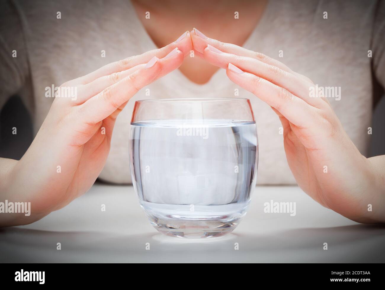 Ein Glas sauberes Mineralwasser von Frau#39;s Hände bedeckt. Umweltschutz Stockfoto