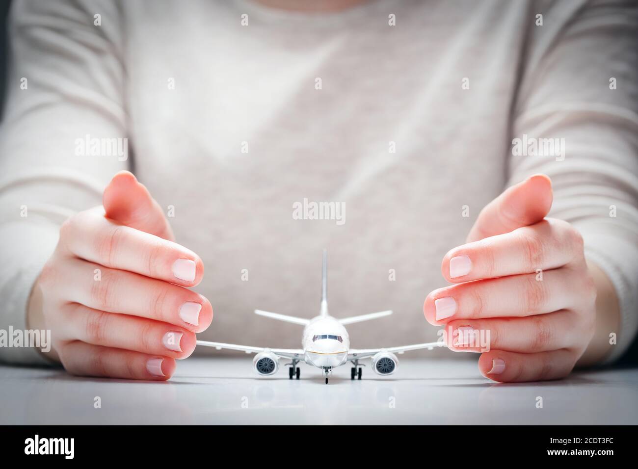 Flugzeugmodell von Händen umgeben in Geste des Schutzes. Sicherheit der Luftfahrtindustrie, Versicherungen Stockfoto