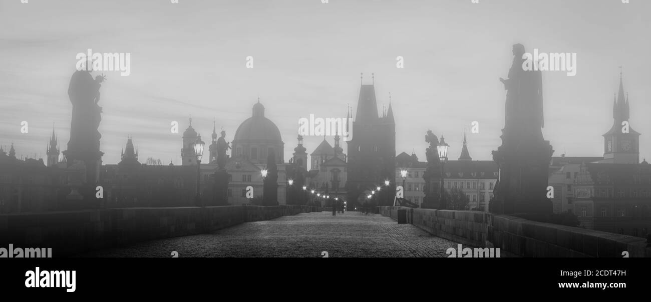 Karlsbrücke im Nebel bei Sonnenaufgang, Prag, Tschechische Republik. Dramatische Statuen und mittelalterliche Türme. Stockfoto
