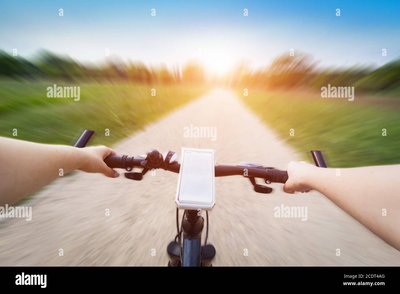 Fahren Sie ein Fahrrad aus der Perspektive der ersten Person. Smartphone am Lenker. Schnelle Bewegungsunschärfe Stockfoto