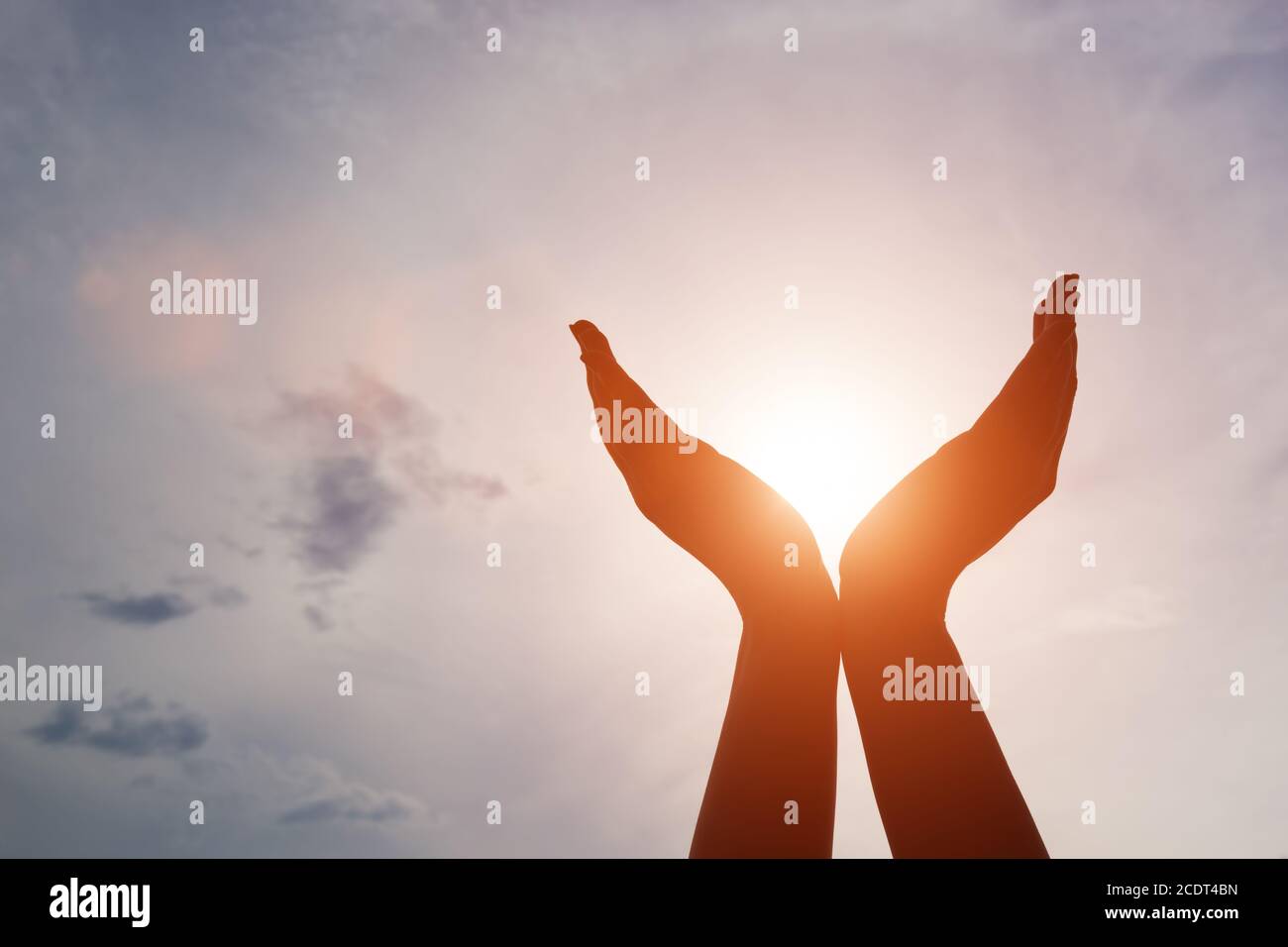 Erhöhte Hände fangen Sonne auf Sonnenuntergang Himmel. Konzept von Spiritualität, Wohlbefinden, positive Energie Stockfoto