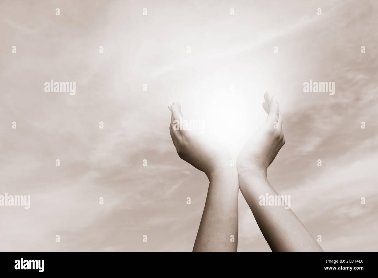 Erhöhte Hände fangen Sonne auf bewölktem Himmel. Konzept von Spiritualität, Wohlbefinden, positive Energie Stockfoto
