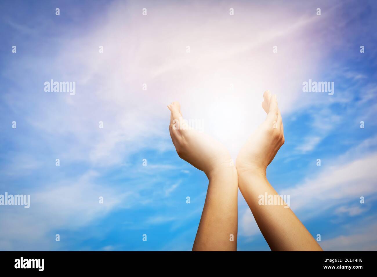 Erhöhte Hände fangen Sonne auf blauem Himmel. Konzept von Spiritualität, Wohlbefinden, positive Energie Stockfoto