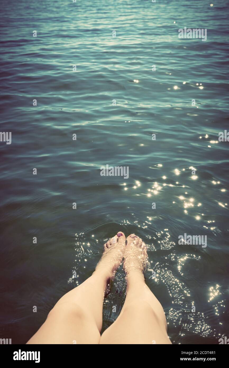Junge Frau, die ihre Beine im Meer benetzt. Sommerferien. Vintage. Stockfoto