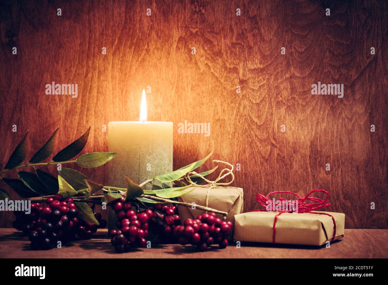 Weihnachtsgeschenke, Geschenke mit einer Kerze, die auf Holzwand Hintergrund leuchtet. Stockfoto