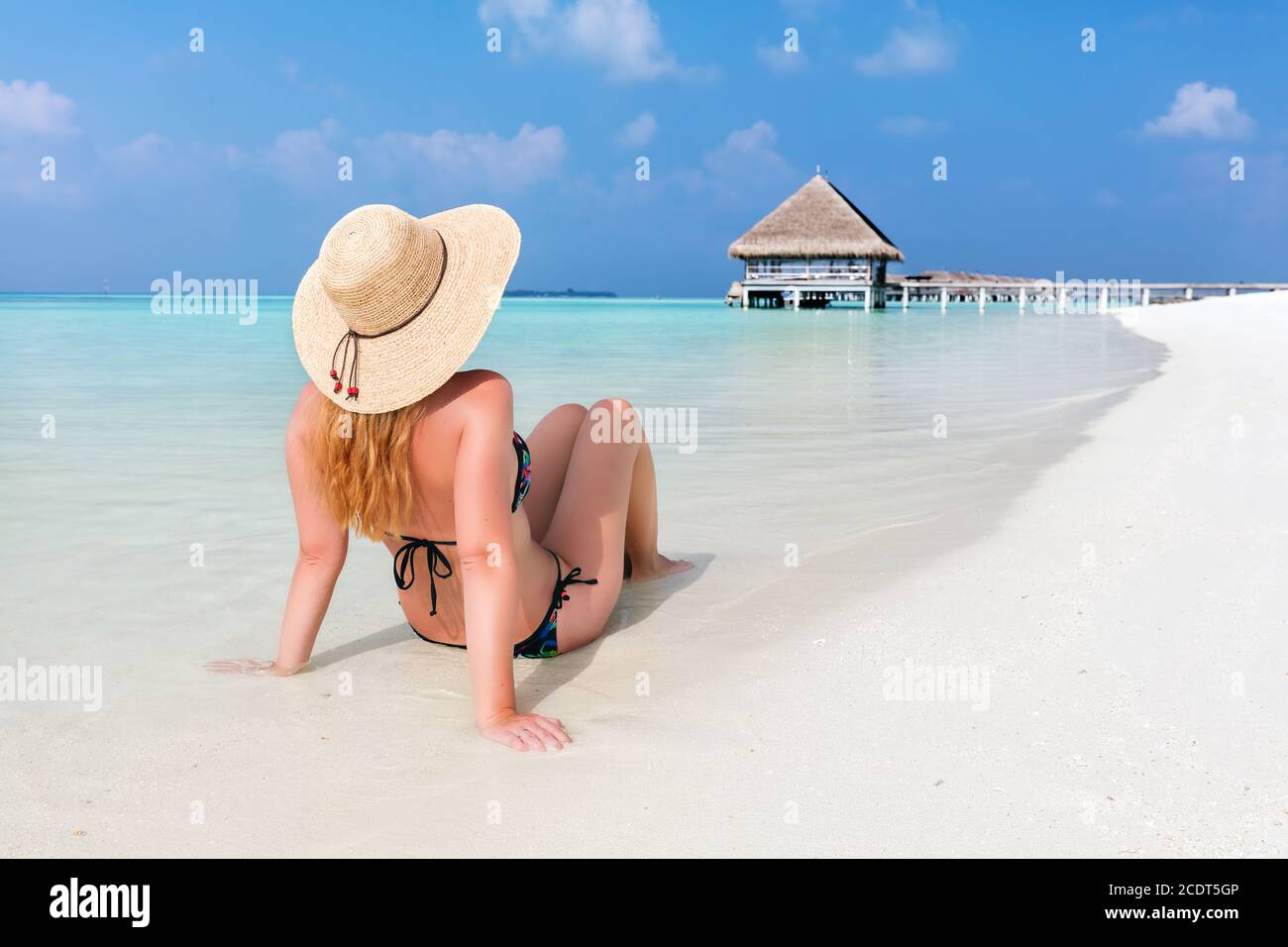 Schöne junge Frau in Sonnenhut sitzen entspannt am tropischen Strand Auf den Malediven Stockfoto