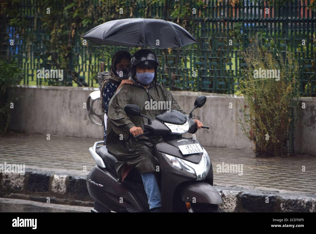 Ein Paar auf einem Motorrad während heftiger Regenfälle in Srinagar, Indien. Stockfoto