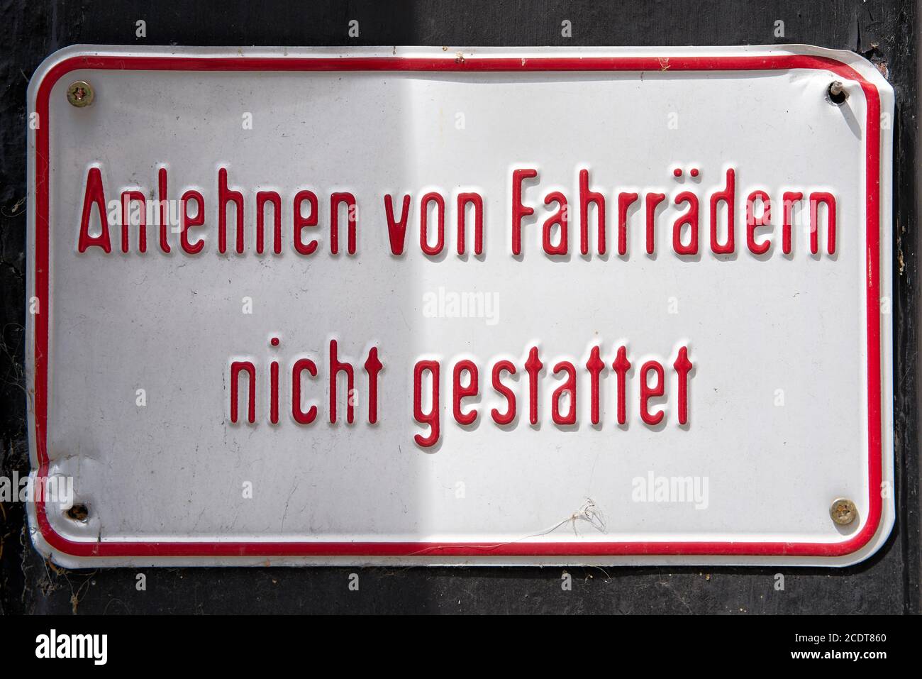 Schild an einer Hauswand mit der Inschrift Schiefen von Fahrräder nicht erlaubt Stockfoto