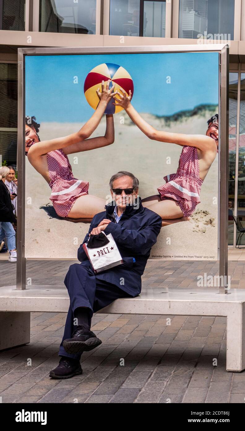 Reifer Mann sitzt am Strand von Retro-Poster, Kings Cross, London, England Stockfoto