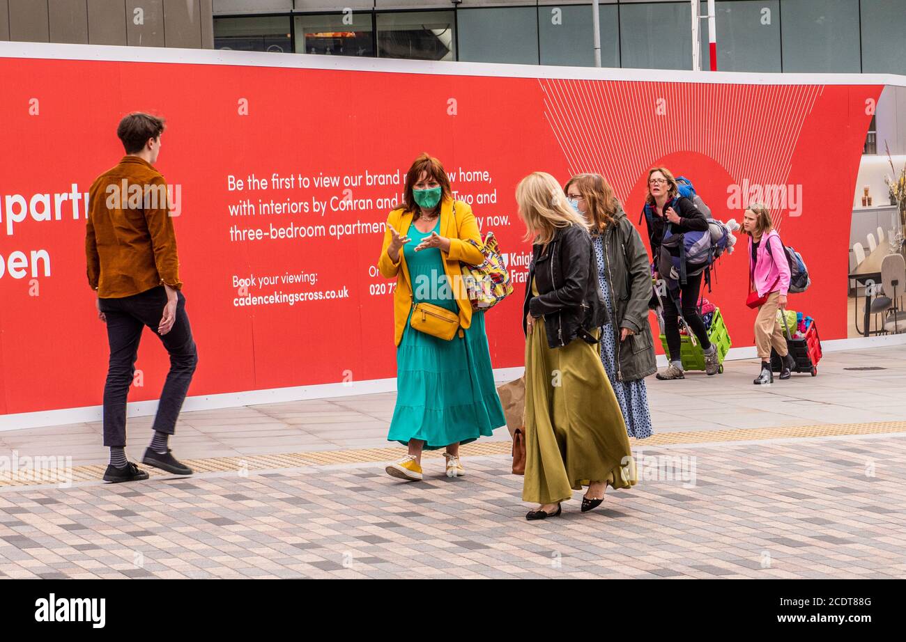 Frau mit Gesichtsbedeckung beim Gehen mit Freund, Kings Cross, London, England Stockfoto