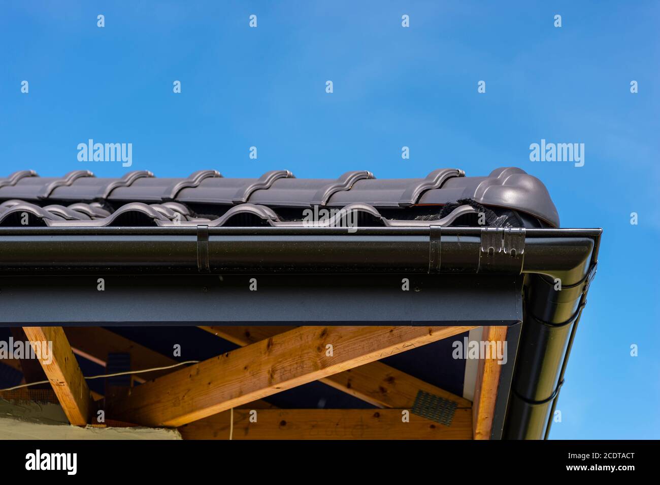 Das Dach eines Einfamilienhauses mit einer neuen Keramikfliesen in anthrazit gegen den blauen Himmel bedeckt, sichtbar Ridge Fliesen. Stockfoto