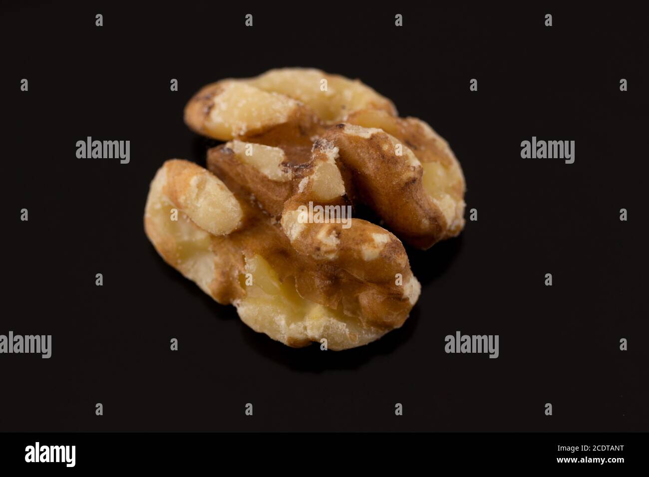 Makroaufnahme einer einzigen Walnusshälfte auf einem schwarzen Hintergrund mit leichter Reflexion Stockfoto