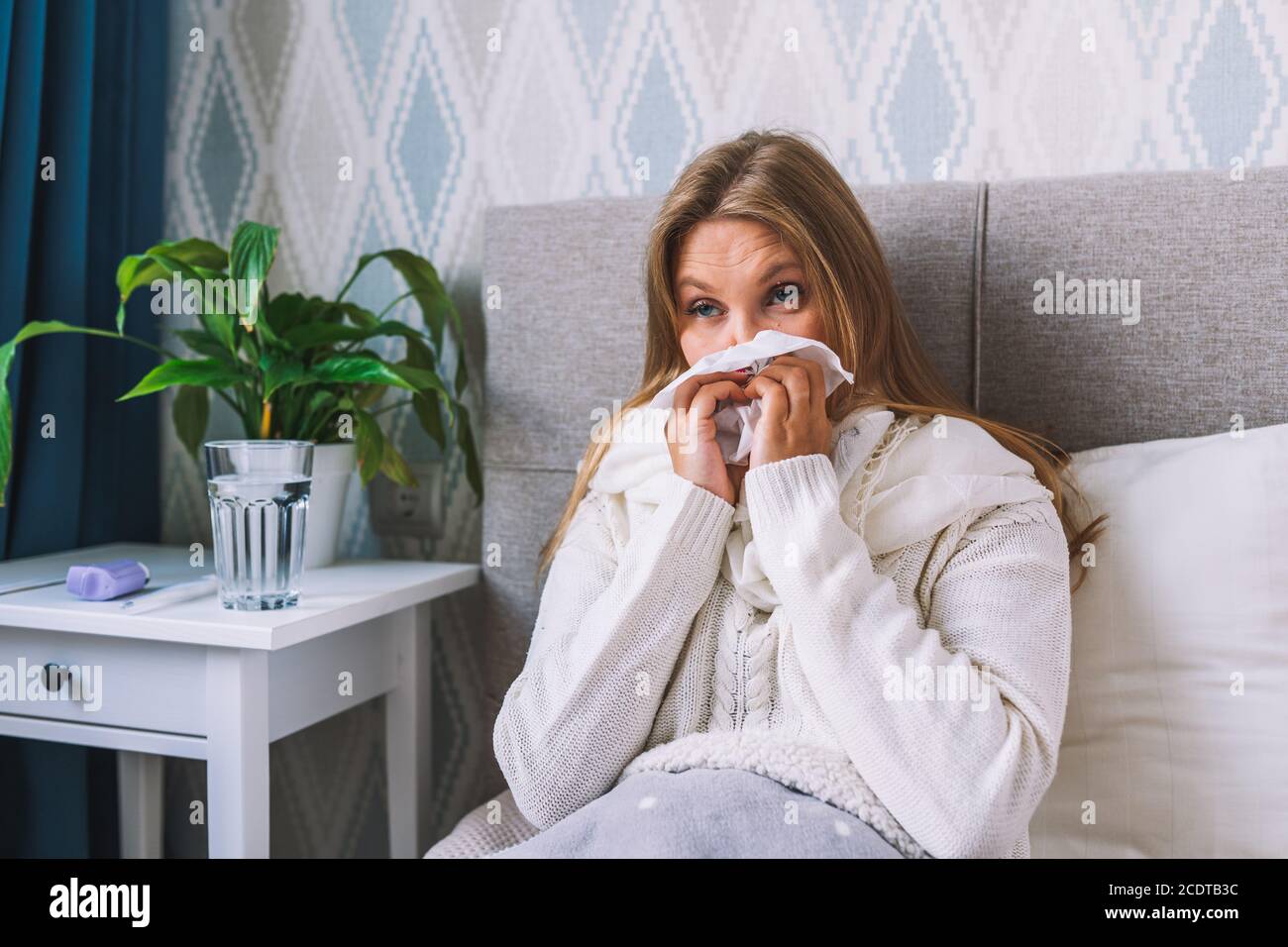 Junge Frau leidet zu Hause an Grippe. Frau bläst ihre Nase hält Gewebe Taschentuch, mit Symptomen der chronischen Sinusitis, saisonale Allergie Stockfoto