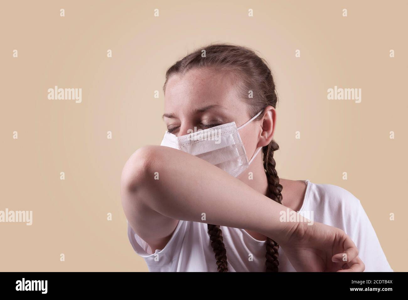 Mädchen in einer medizinischen Maske. Mädchen auf einem gelben Hintergrund. Das Mädchen niest, hustet. Stockfoto
