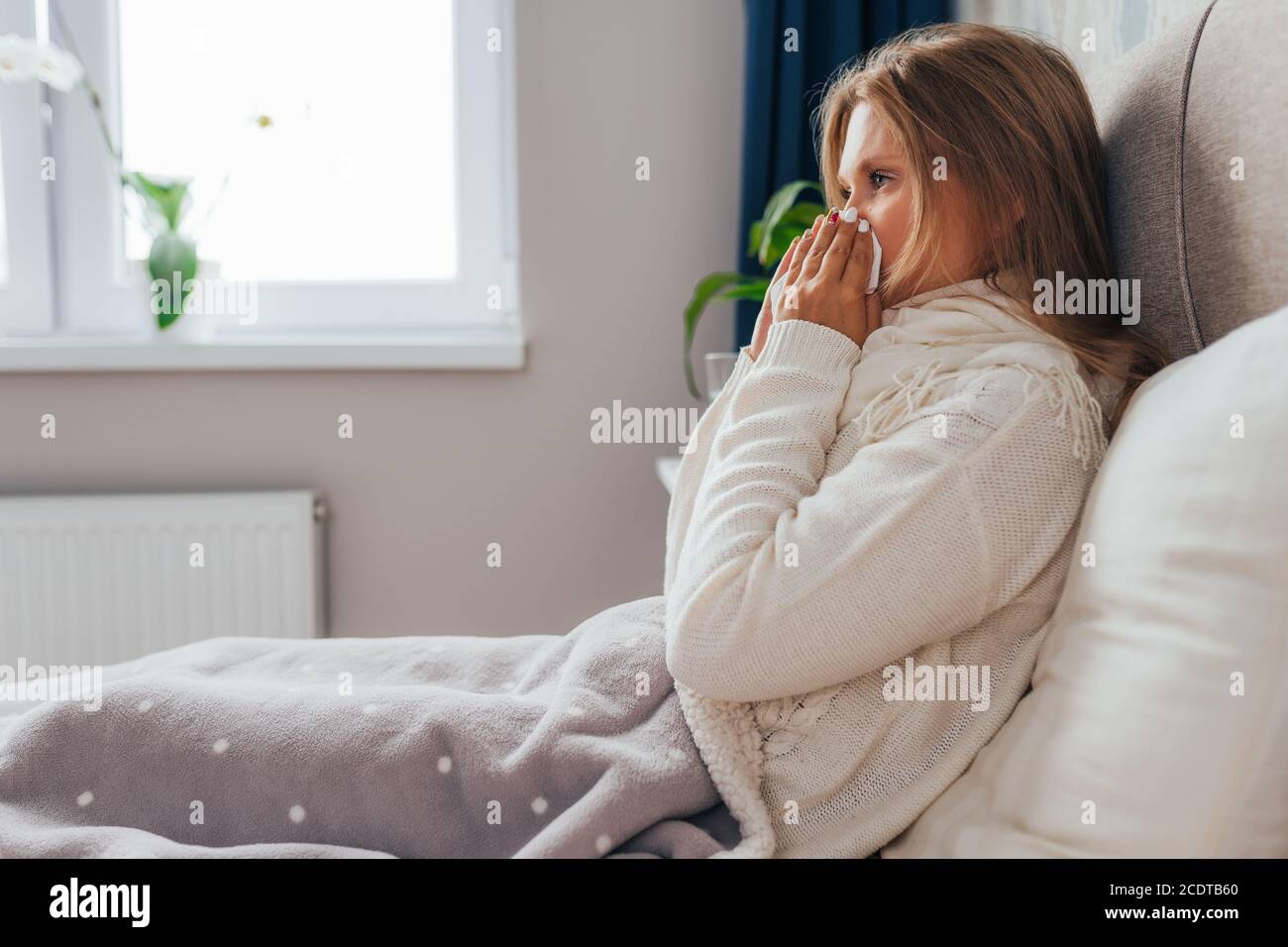 Junge Frau leidet zu Hause an Grippe. Frau bläst ihre Nase hält Gewebe Taschentuch, mit Symptomen der chronischen Sinusitis, saisonale Allergie Stockfoto