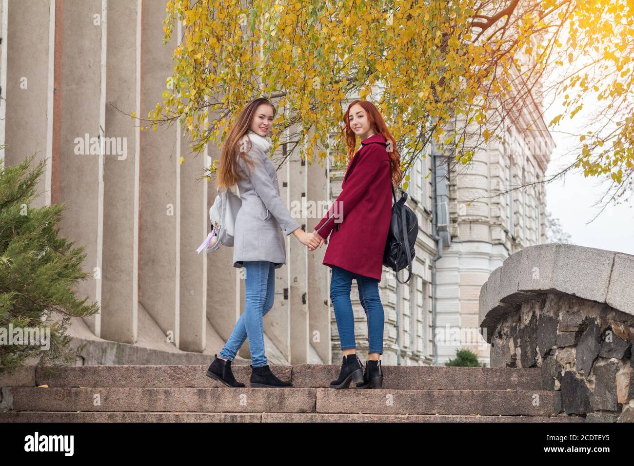 Zwei weibliche Teenager, die zu Fuss Stein Schritte halten sich an den Händen im Herbst Stadt. Stockfoto