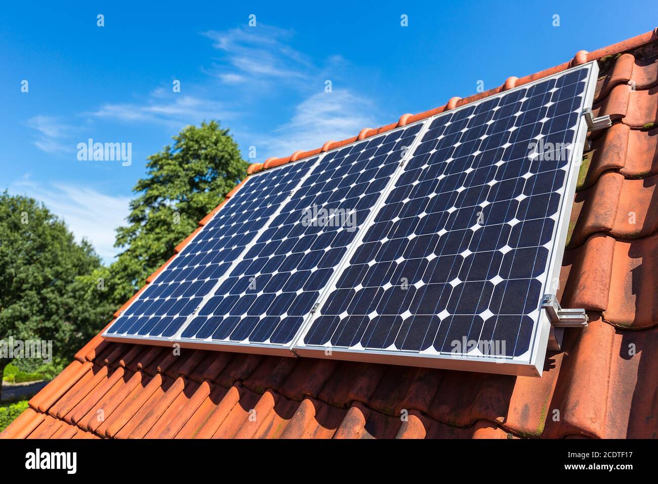 Reihe von Sonnenkollektoren auf orangefarbenem Dach Stockfoto