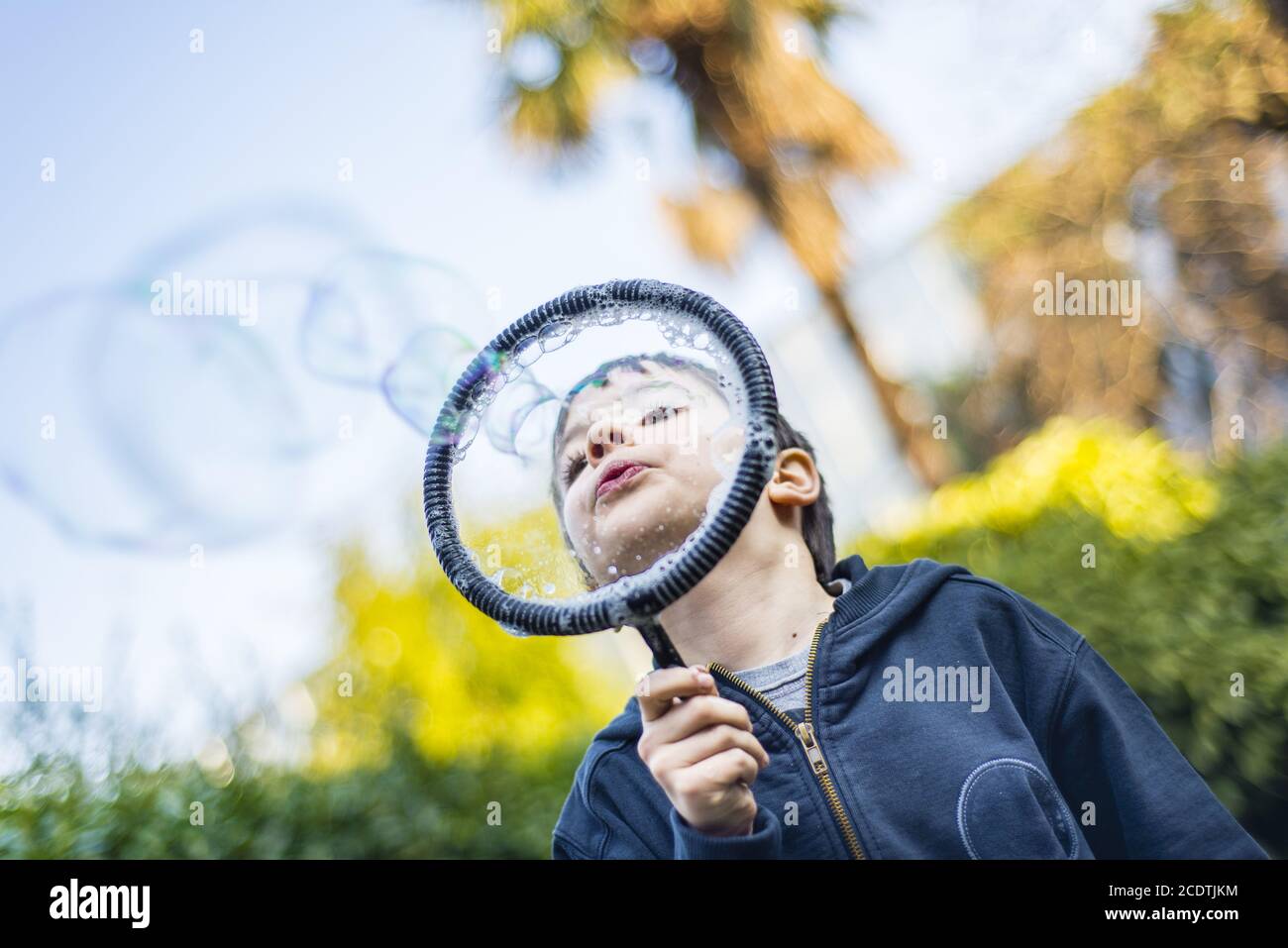7-jährige Kind im Garten im Winter macht grosse Seifenblasen Stockfoto