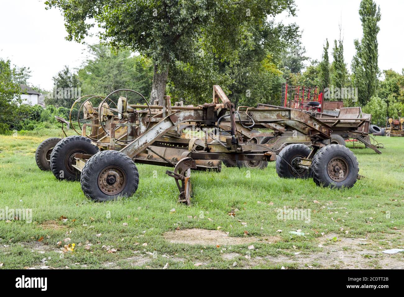 Grader auf einem Anhänger für schwere Ausrüstung. Anhängerkupplung für Traktoren und Mähdrescher. Anhänger für Landmaschinen Stockfoto