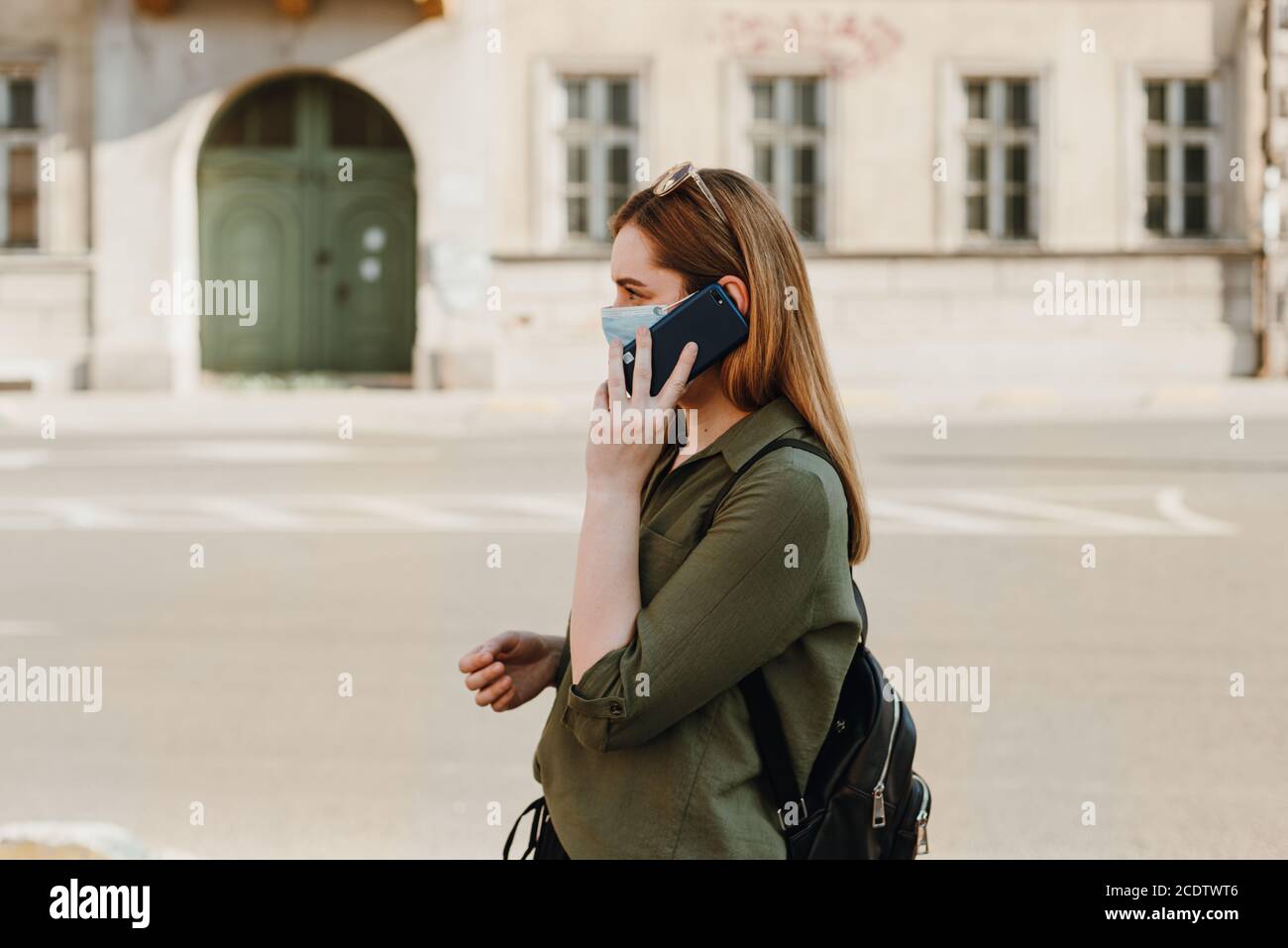 Mädchen mit Maske sprechen am Telefon auf der Straße Stockfoto