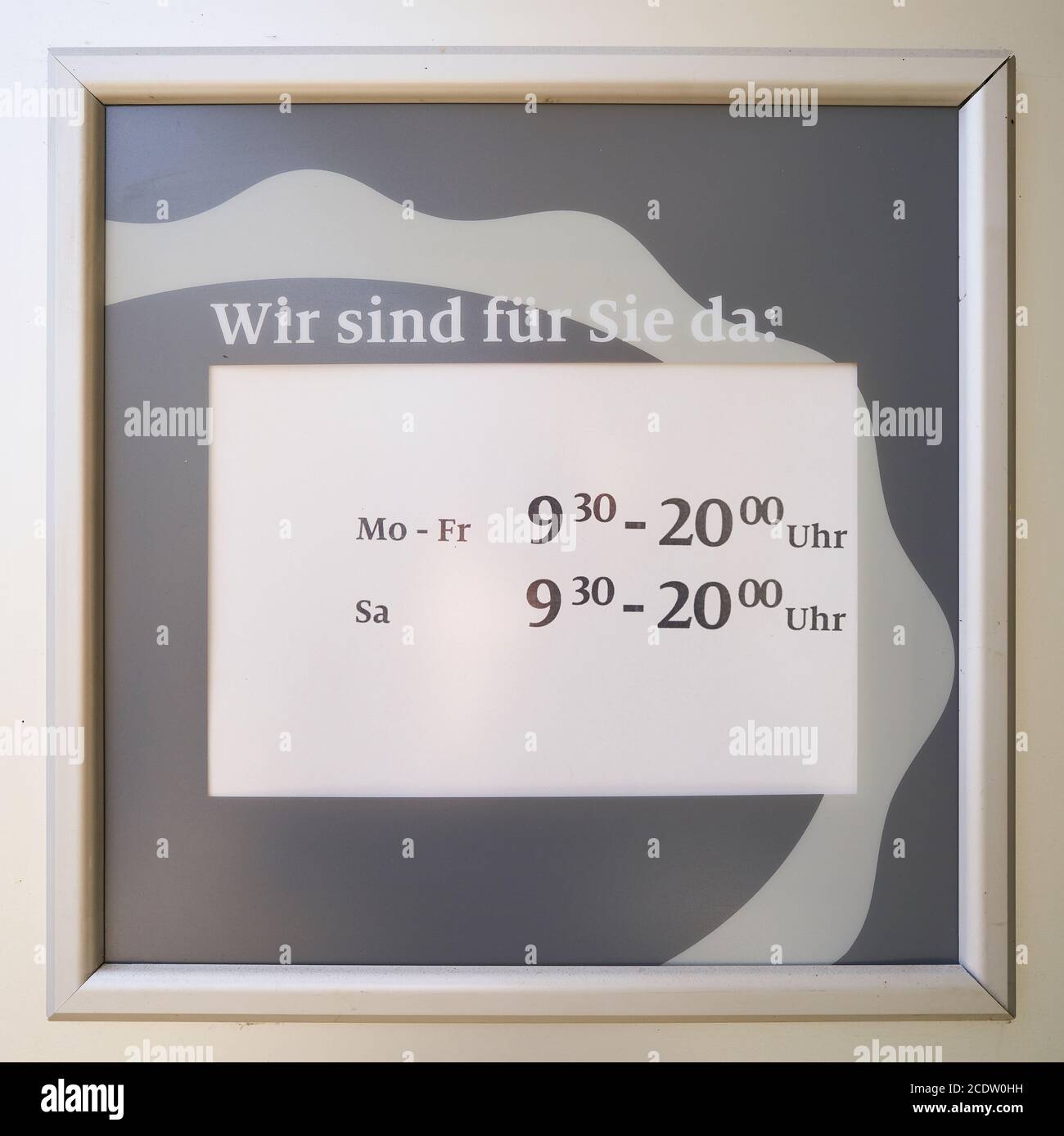 Unterschreiben Sie mit den Öffnungszeiten des Stores hinter dem Fenster von Ein Geschäft in Deutschland Stockfoto