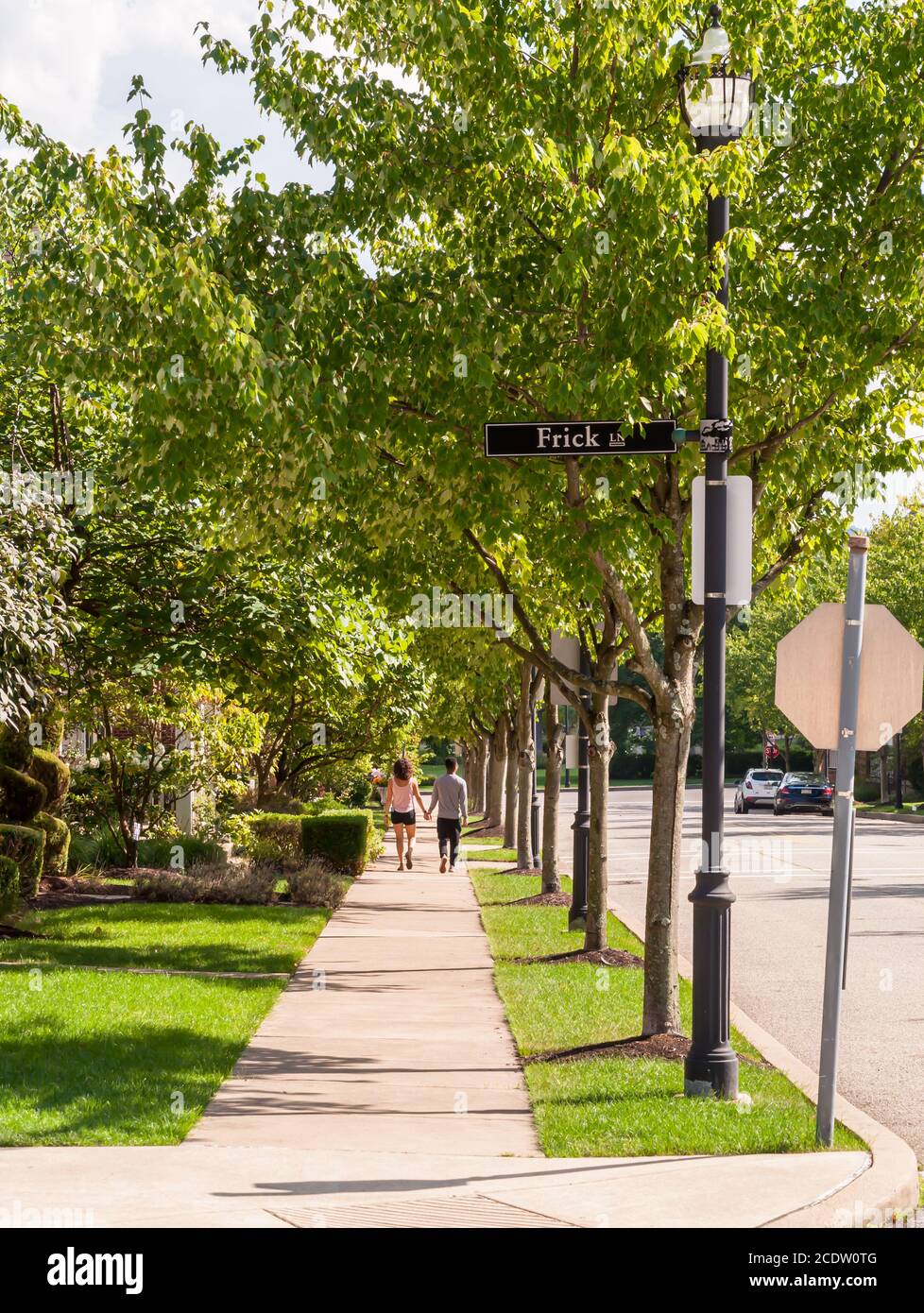 Ein junges Paar, das an einem sonnigen Sommertag in einem Wohngebiet im Summerset-Viertel Hand in Hand geht, Pittsburgh, Pennsylvania, USA Stockfoto