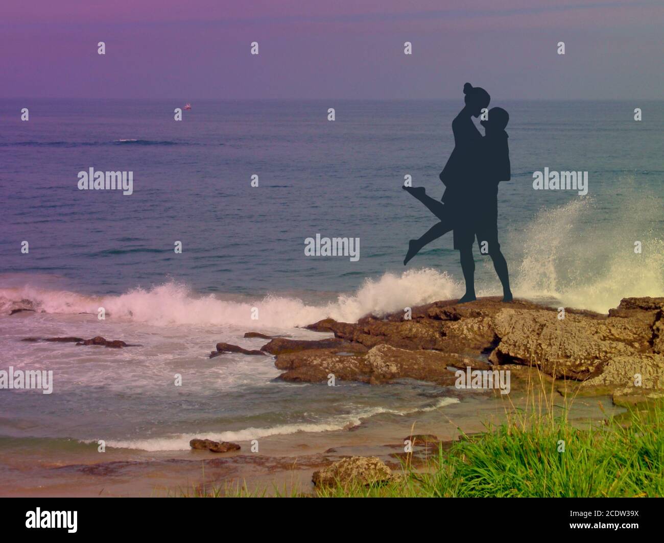 Romantisches Paar am Strand bei Sonnenuntergang mit Wellen Krachend auf den Felsen Stockfoto