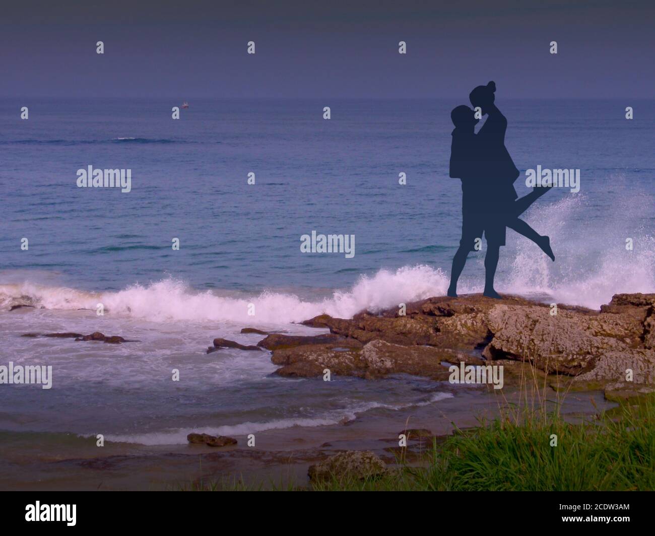 Romantisches Paar am Strand bei Sonnenuntergang mit Wellen Krachend auf den Felsen Stockfoto