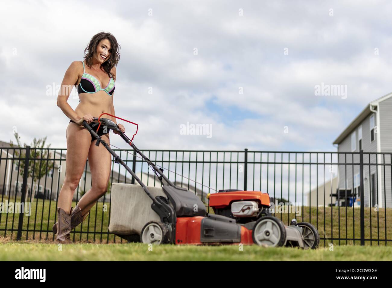 Ein wunderschönes Bikini-verkleidetes Modell, das den Rasen mäht Stockfoto
