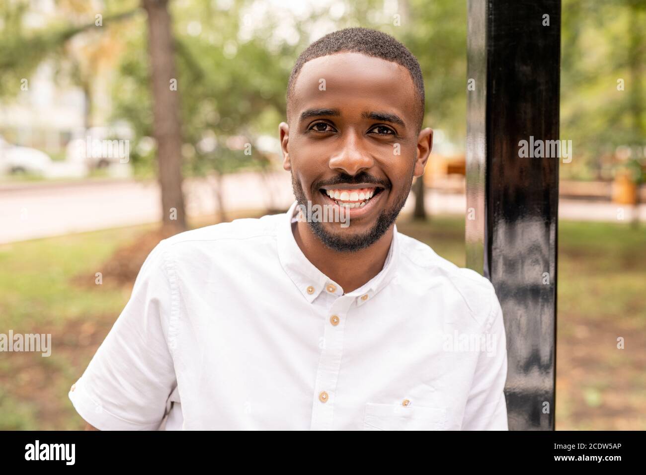 Junger fröhlicher Mann afrikanischer Ethnie, der dich mit anschaut Weiß toothy Lächeln Stockfoto