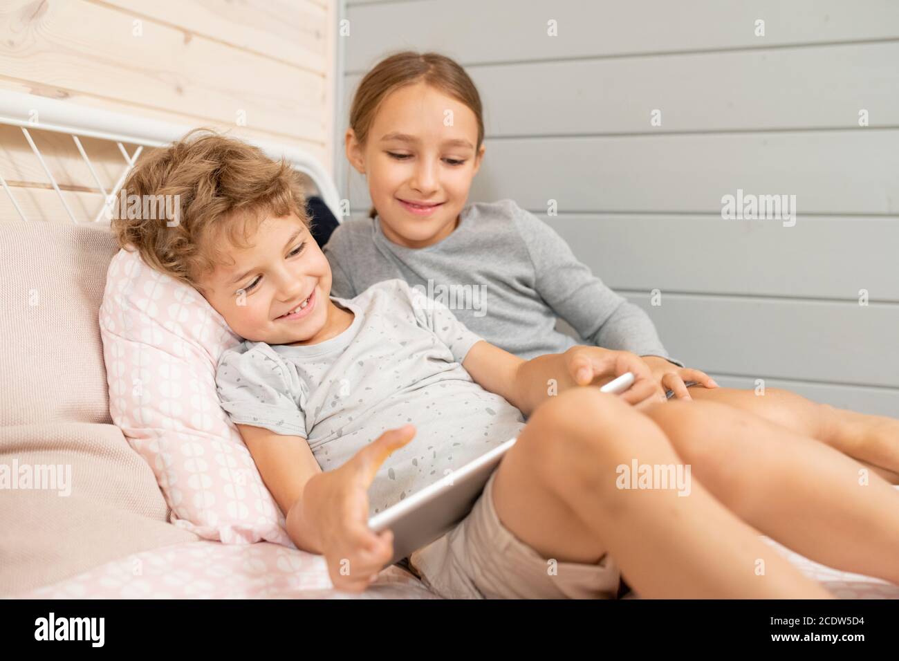 Happy niedlichen kleinen Jungen und seine glückliche Schwester in Homewear Online-Cartoons ansehen Stockfoto