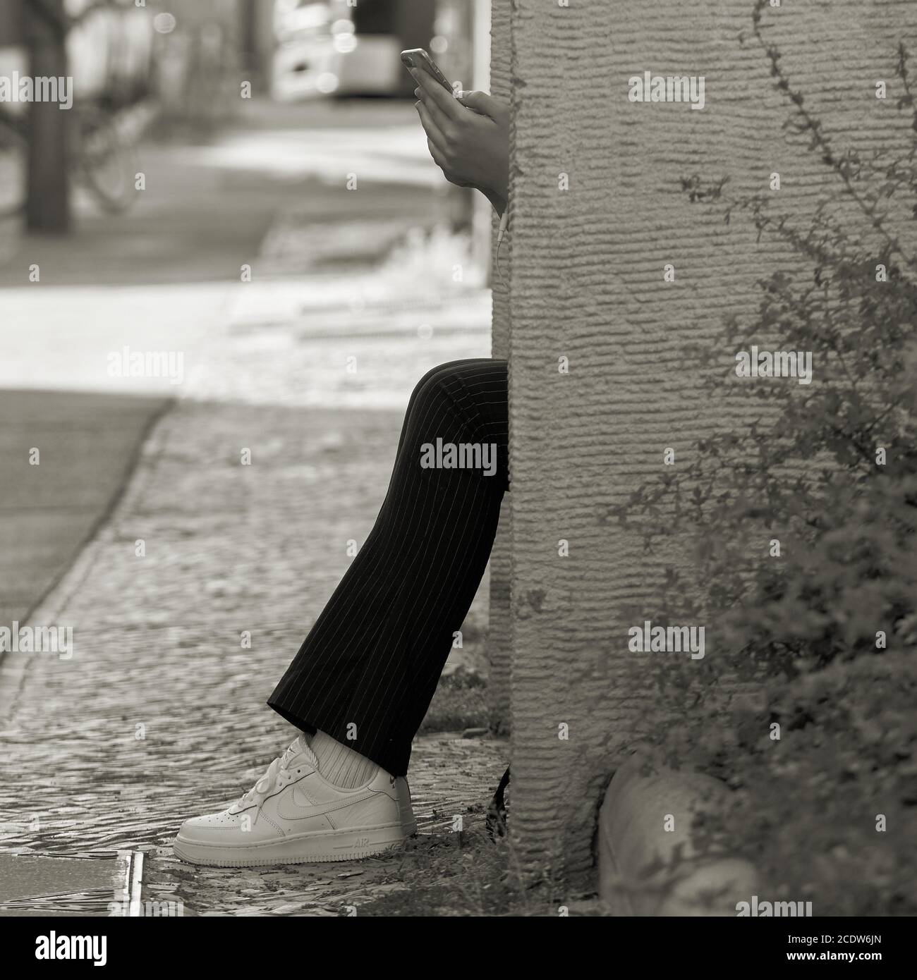 Junge Frau auf ein Schritt in Berlin sitzen und tippen auf dem Smartphone Stockfoto