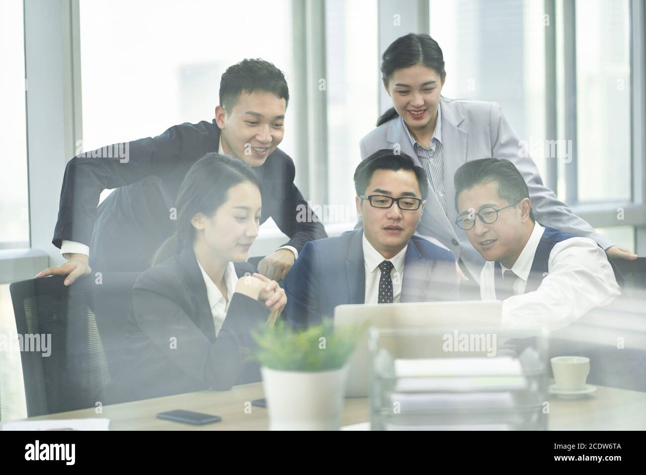 Durch-das-Glas-Aufnahme einer Gruppe von asiatischen Geschäftsführern Männer Und Frauen treffen sich im Büro mit Laptop-Computer Stockfoto