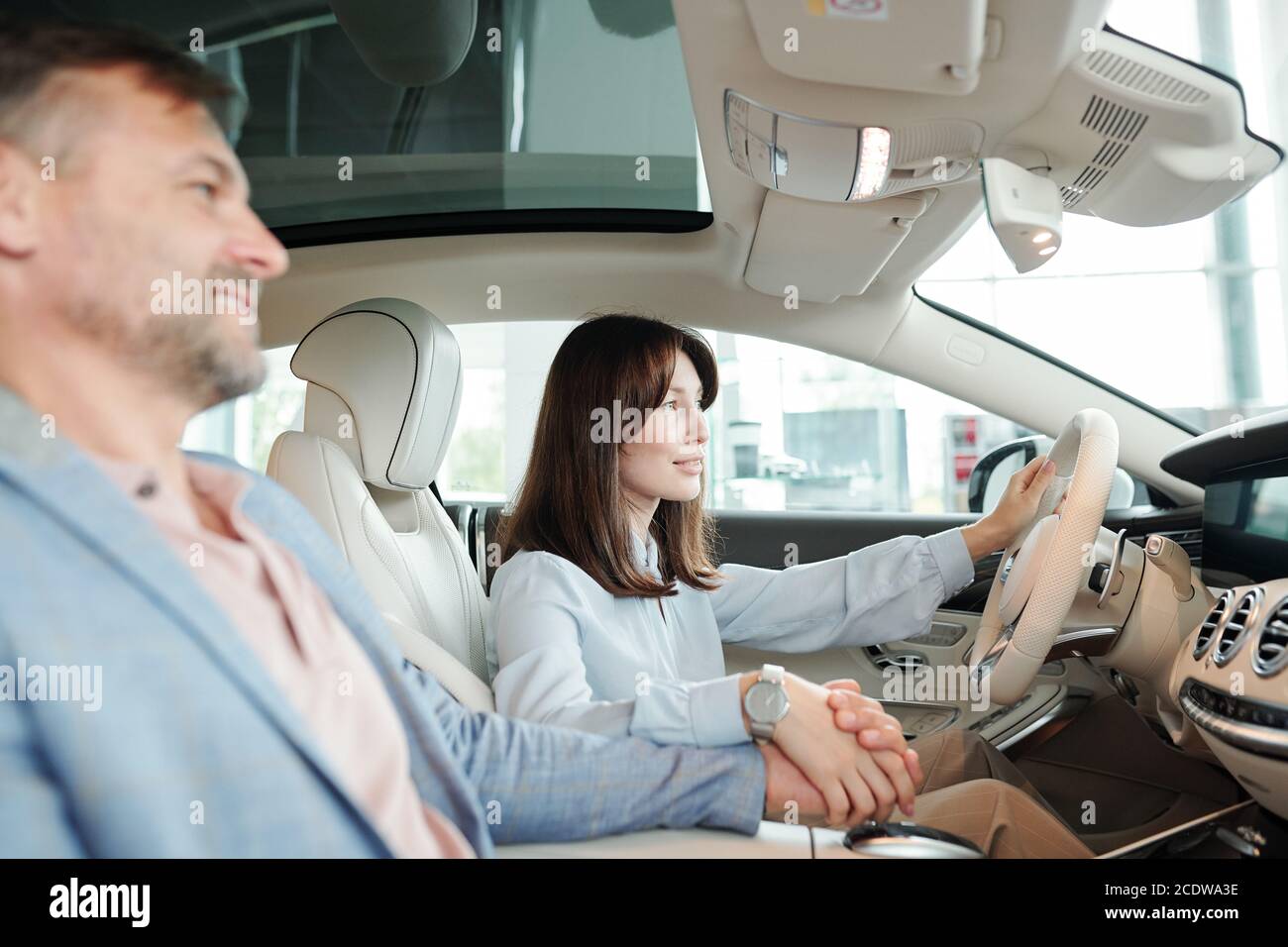Ziemlich junge weibliche Klientin der Auto-Mitte hält durch Steer Während der Probefahrt Stockfoto