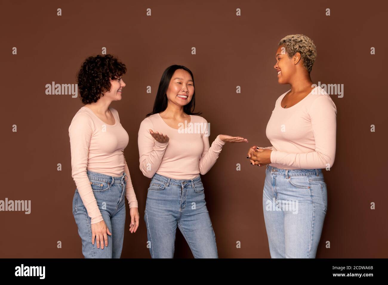 Gruppe von jungen lächelnden Frauen in weißen Pullovern im Chat Vorderseite der Kamera Stockfoto