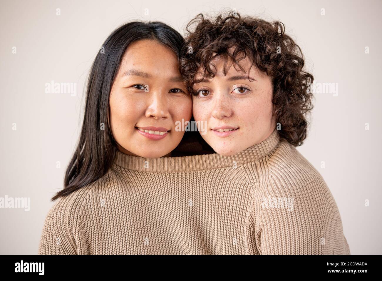 Junge asiatische und kaukasische Frauen mit dunklen Haaren in einem Strickpullover aus Baumwolle Stockfoto