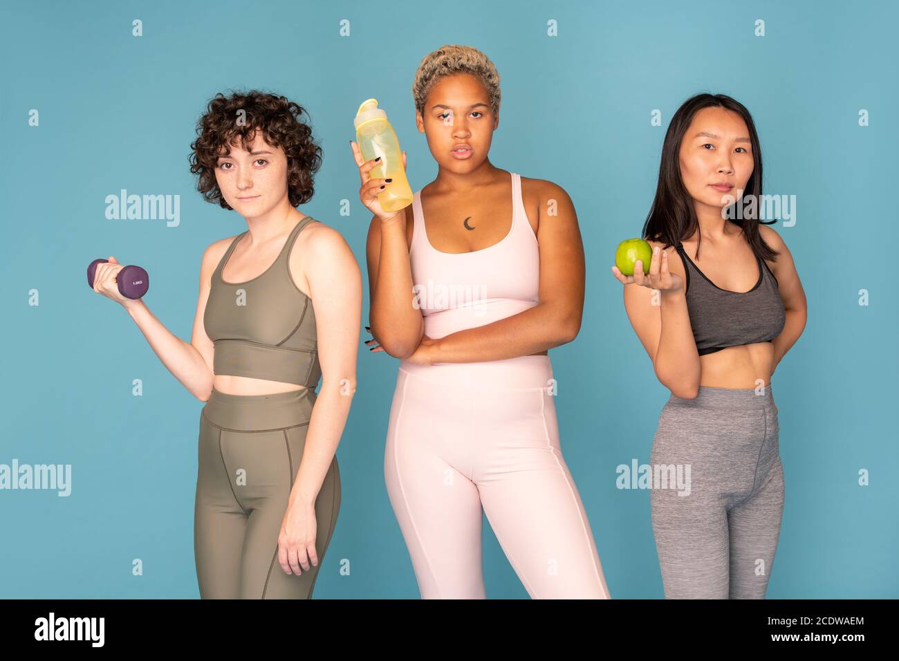 Drei junge, ziemlich aktive Frauen verschiedener Ethnien in Trainingsanzügen Stockfoto