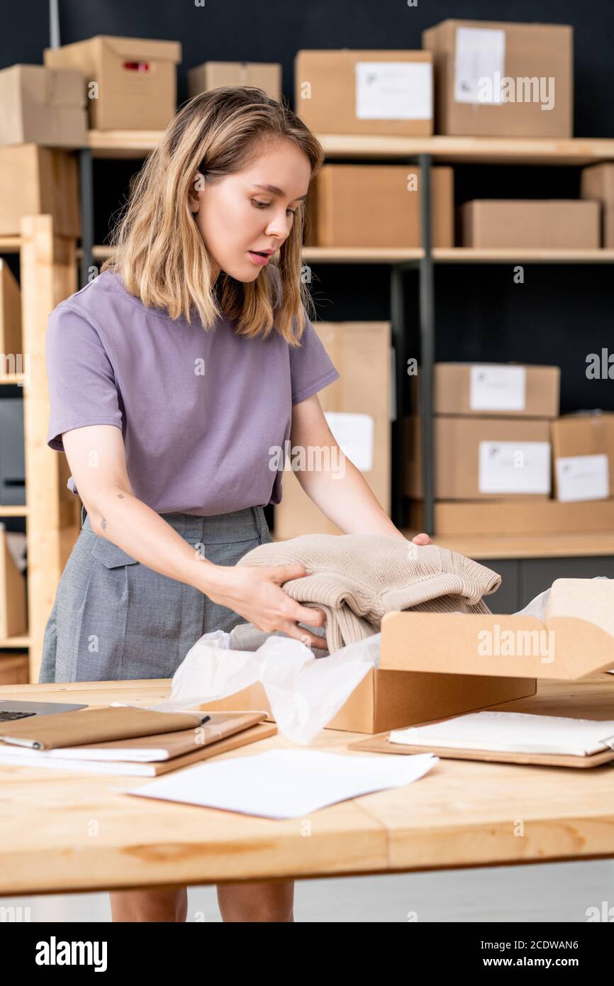 Junge Manager von Online-Shop Putting gefalteten Strickpullover in Karton Stockfoto