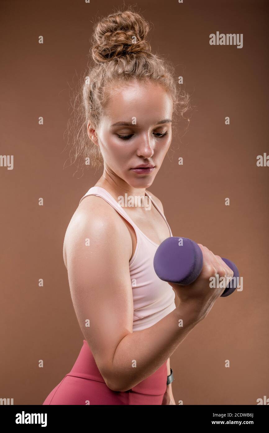 Junge seriöse starke Hündin in Sportbekleidung Training mit Hantel in Isolation Stockfoto