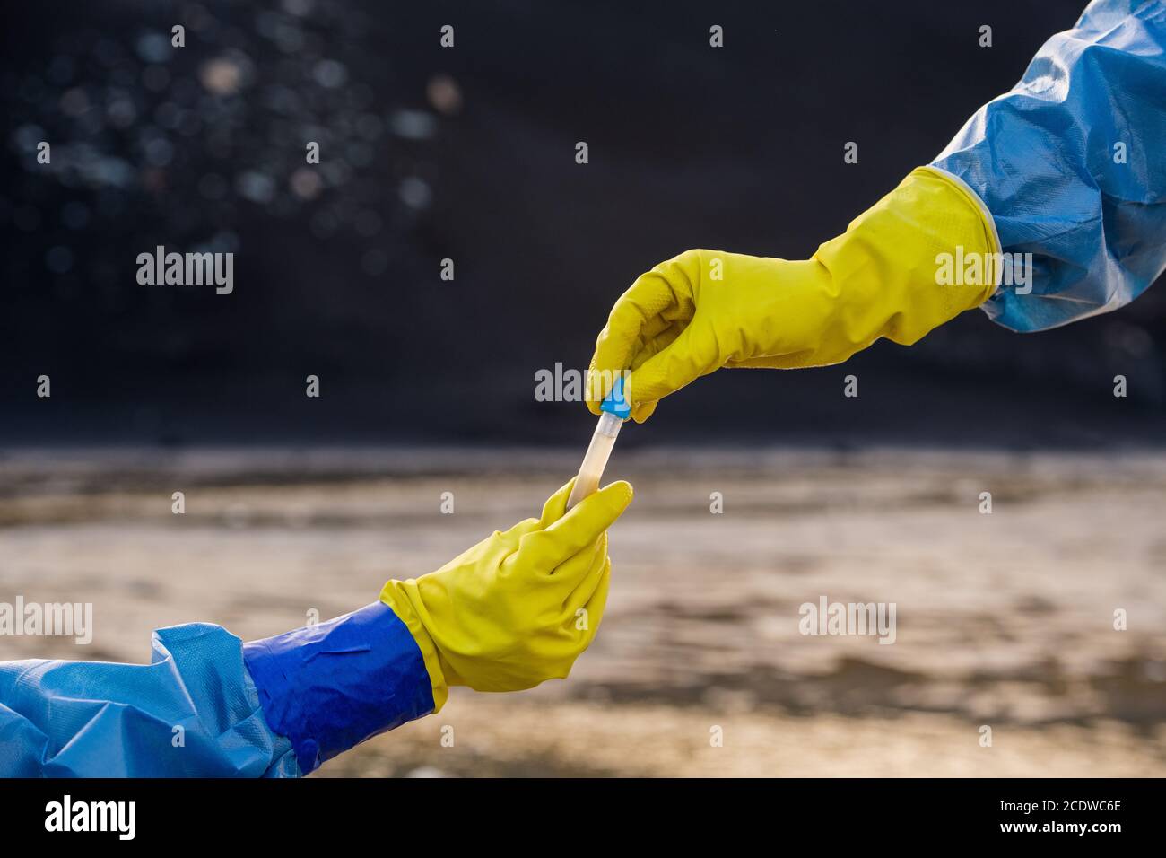 Handschuhen der Ökologen in Overalls unter der Flasche mit Probe Verschmutztes Wasser Stockfoto