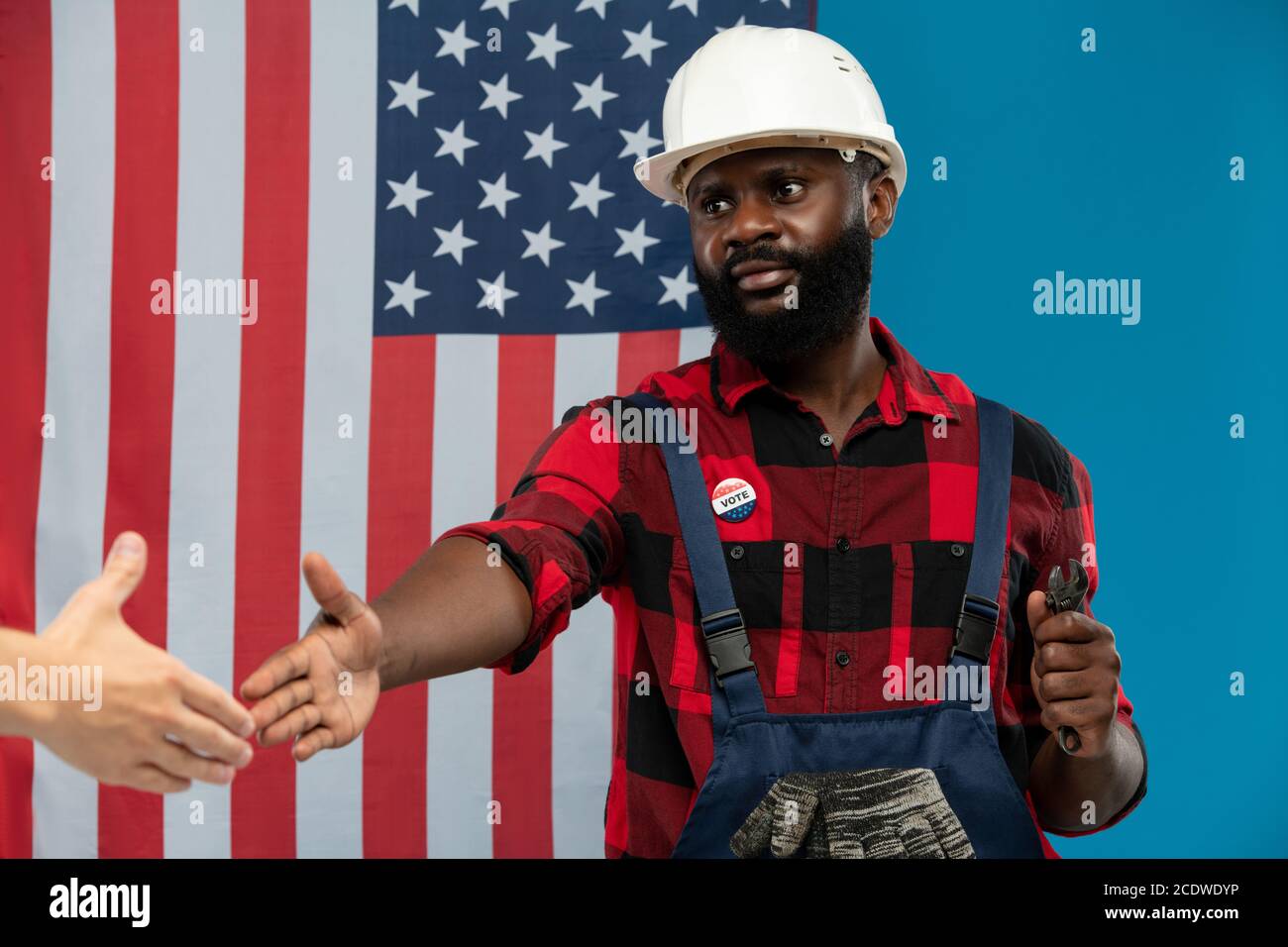 Junger erfolgreicher Reparaturmann afrikanischer Ethnie, der Weiß die Hand gibt Kollege Stockfoto