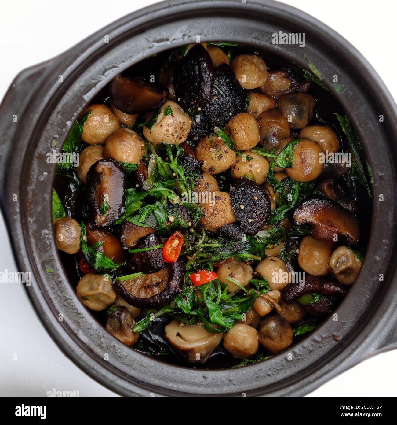 Draufsicht Topf mit Lebensmitteln auf weißem Hintergrund, Strohpilz, Agaric Koch mit Sauce und Chili, Pfeffer zu köstlichen vietnamesischen veganen Gericht zum Mittagessen zu machen Stockfoto